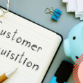 Open agenda on grey desk. Text on the agenda reads: customer acquisition