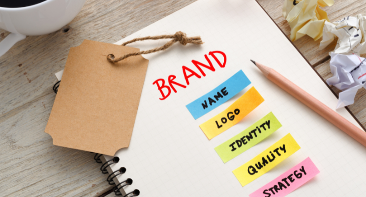 A notepad with 'brand' written on it and post-it notes with the following words name logo identity quality strategy