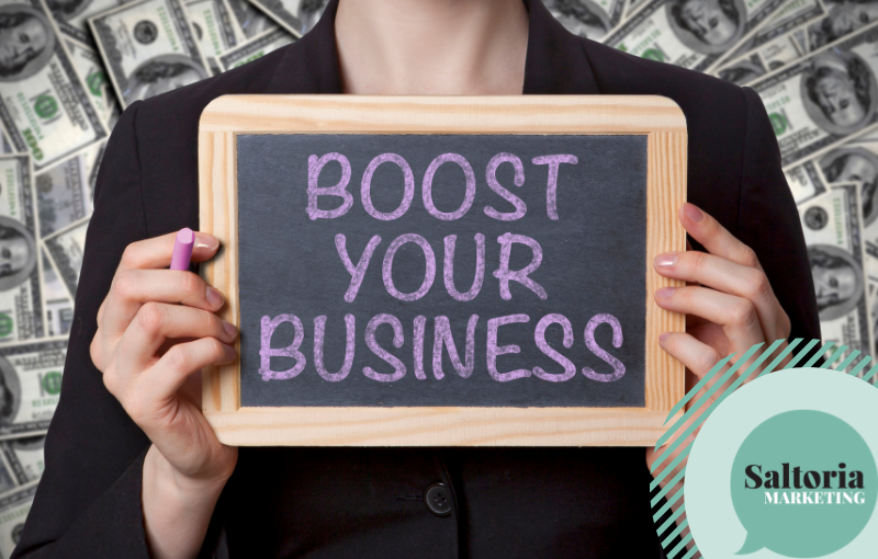 Girl holding balckboard. Text on blackboard reads "boost your business". The picture reflects the title of the blog "14 tips for small business marketing"