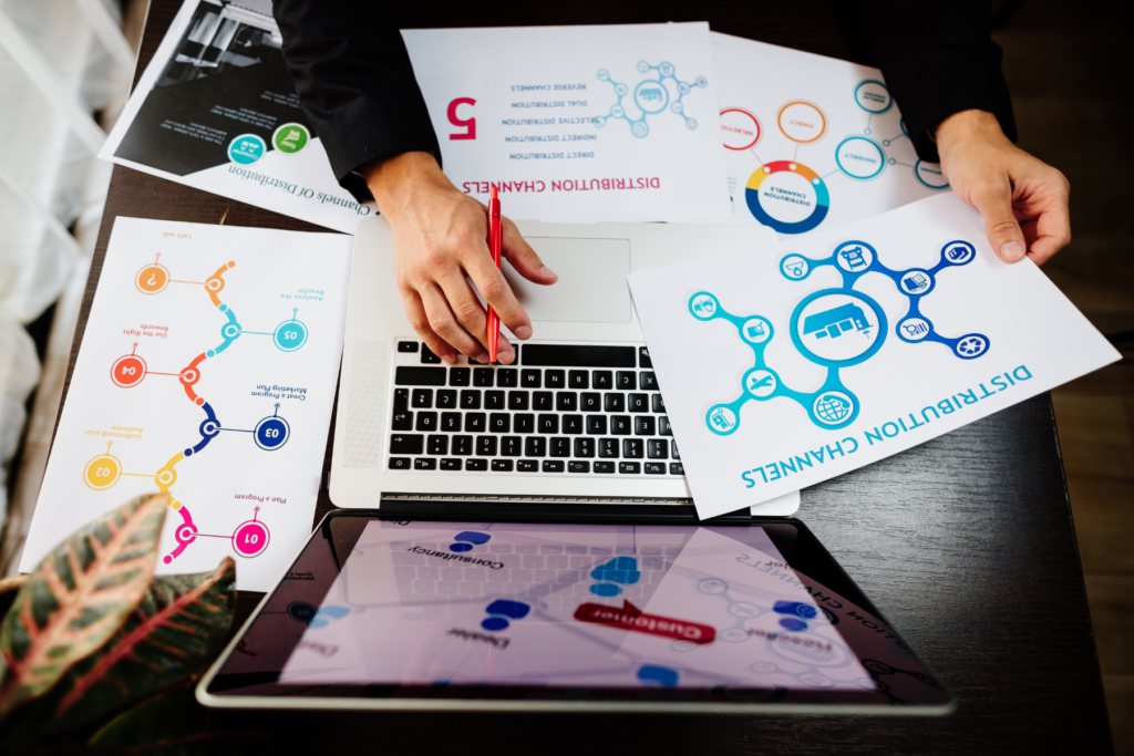 laptop with lots of paper and visuals suggesting planning a content distribution strategy